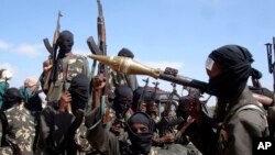 FILE - Armed al-Shabab fighters ride on pickup trucks just outside the Somali capital of Mogadishu, Dec. 8, 2008. 