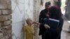 FILE - A police officer stands guard as a health worker administers a polio vaccine to a child at a neighborhood of Peshawar, Pakistan, May 22, 2023. 