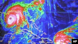 FILE - Hurricane Ivan seen on the computer screen at the National Hurricane Center in Miami, Wednesday, Sept. 15, 2004, seen 250 miles from the Gulf Coast, and Tropical Storm Jeanne is seen as it approaches Puerto Rico.