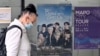 FILE - A woman walks past a poster featuring members of the K-pop group BTS, at a tourist information center in Seoul, South Korea, June 15, 2022.