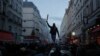 A members of Kurdish community stands on the top of a car during clashes with police officers near the crime scene where a shooting took place in Paris, Dec. 23, 2022.
