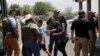 Un niño se sube a un autobús escolar mientras el personal policial vigila la escena de un tiroteo en la Escuela Primaria Robb en Uvalde, Texas, el 24 de mayo de 2022.