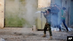 FILE - Libyan military soldiers fire weapons during clashes with Islamic militias in Benghazi, Oct. 29, 2014.