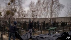 Punonjësit sjellin në varrezat e qytetit Bucha kufomat që gjenden (5 prill 2022)