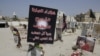 FILE- Religious flags, photographs and tributes to 21 victims of a suicide bombing, claimed by the Islamic State group, of a Shiite mosque are seen attached to their graves at a cemetery in Qudeeh, Saudi Arabia, May 30, 2015.