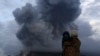 Seorang ibu dan anaknya menyaksikan letusan Gunung Sinabung dari desa Berastepu, kabupaten Karo, Sumatera Utara (10/1). (Reuters/Beawiharta)