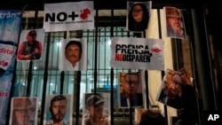 Foto-foto para wartawan yang terbunuh dipasang di sebuah pagar saat berlangsungnya aksi protes nasional terhadap pembunuhan wartawan Lourdes Maldonado dan wartawan foto lepas Margarito Martínez, di Mexico City, Selasa, 25 Januari 2022. (AP/Eduardo Verdugo)