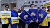 香港新民主同盟成员手持示威道具护照，讽刺孟晚舟拥有3本香港特区护照，质疑入境处滥发香港特区护照。 (摄影: 美国之音汤惠芸)