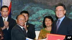 Wu Bangguo, chairman of the Standing Committee of the National People's Congress (NPC) of China, second right, and Heng Samrin, president of the Cambodian National Assembly shake hands after exchanging documents on cooperation between NPC and the Cambodia