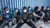 ARCHIVES - Des migrants assis à l'extérieur d'un centre de migrants temporaires après avoir traversé la barrière frontalière de l'enclave nord-africaine espagnole de Melilla, en Espagne, le 19 janvier 2021.