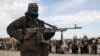 FILE - A member of the Taliban and other people stand at the site during the execution of three men in Ghazni Province, Afghanistan, April 18, 2015. On Feb. 22, 2024, Taliban authorities publicly executed two men convicted of murder in separate cases.