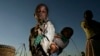 FILE - A young girl carries her sister through a cornfield in Masongo village outside Lilongwe, Malawi, May 13, 2008. 