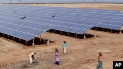 Buruh di India bekerja dekat panel tenaga surya di Gujarat Solar Park di Charanka, distrik Patan. 