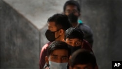 ভারতের নয়াদিল্লিতে একটি সরকারি স্কুলে কয়েকজন কিশোর অপেক্ষা করছে কোভিড-১৯ টিকা নেওয়ার জন্য । ৩ জানুয়ারী, ২০২২, ছবি- এপি
