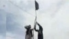 FILE - IS-Khorasan group members mount a flag in a tribal region of Afghanistan, Nov. 2, 2015. 