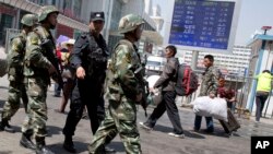 FILE - Armed Chinese paramilitary policemen march past the site of an explosion outside the Urumqi South Railway Station in Urumqi in northwest China's Xinjiang Uygur Autonomous Region, May 1, 2014.