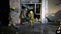 Afghan firefighters spray water at the site of a suicide attack targeting parliamentarian Gul Pacha Mujedi in Kabul, Afghanistan, March 29, 2015. 