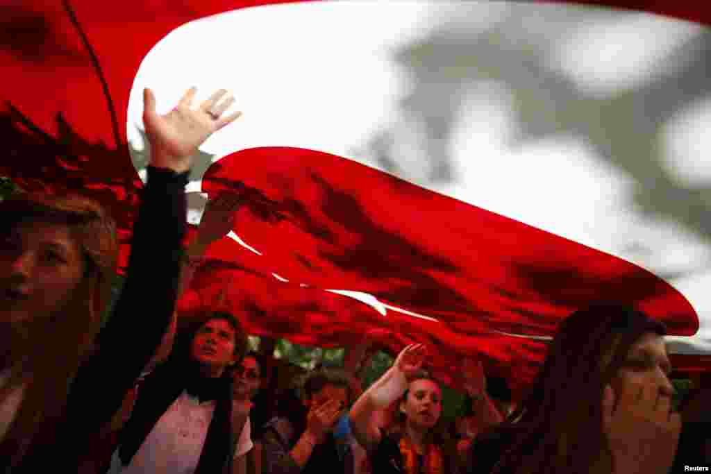 Para demonstran membawa bendera Turki dan meneriakkan slogan-slogan anti-pemerintah dalam demonstrasi di Taman Gezi dekat Alun-Alun Taksim, Istanbul (3/6).