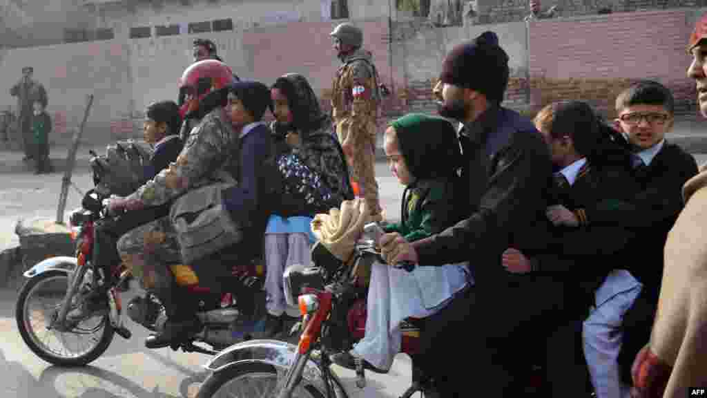 Des parents pakistanais quittent avec leurs enfants à proximité du lieu d&#39;une attaque par des hommes armés talibans sur une école à Peshawar, le 16 décembre 2014.