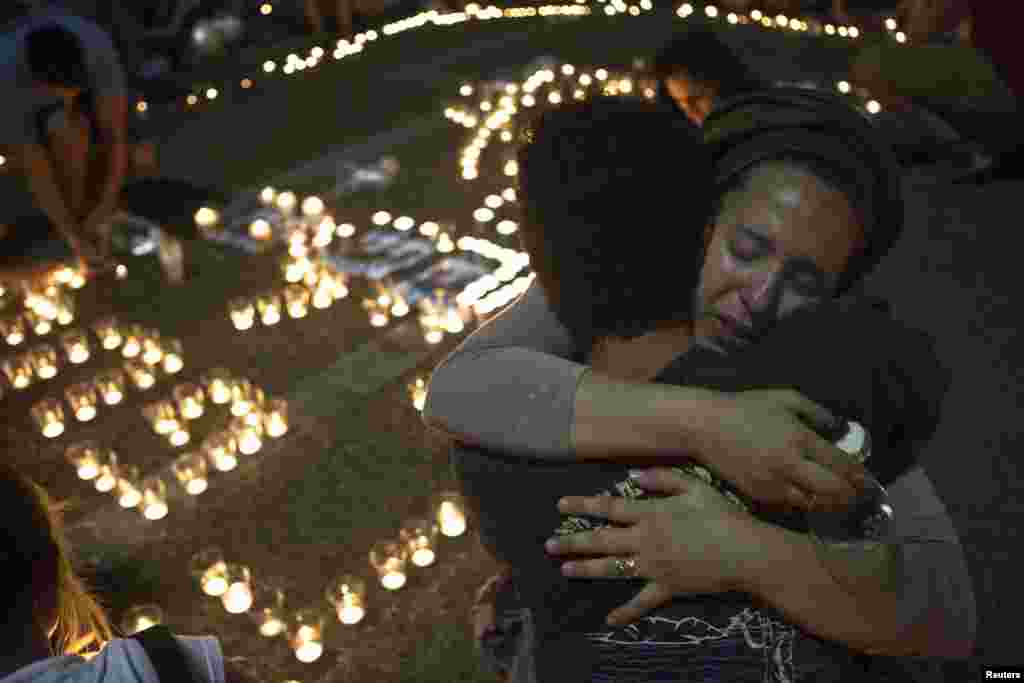 Israeli women hug each other as people light candles in Tel Aviv's Rabin Square as they mourn the death of three teenagers who were abducted, June 30, 2014.
