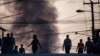 Residentes caminan frente a una columna de humo durante la escasez de combustible en Puerto Príncipe, Haití, el 26 de octubre de 2021. 