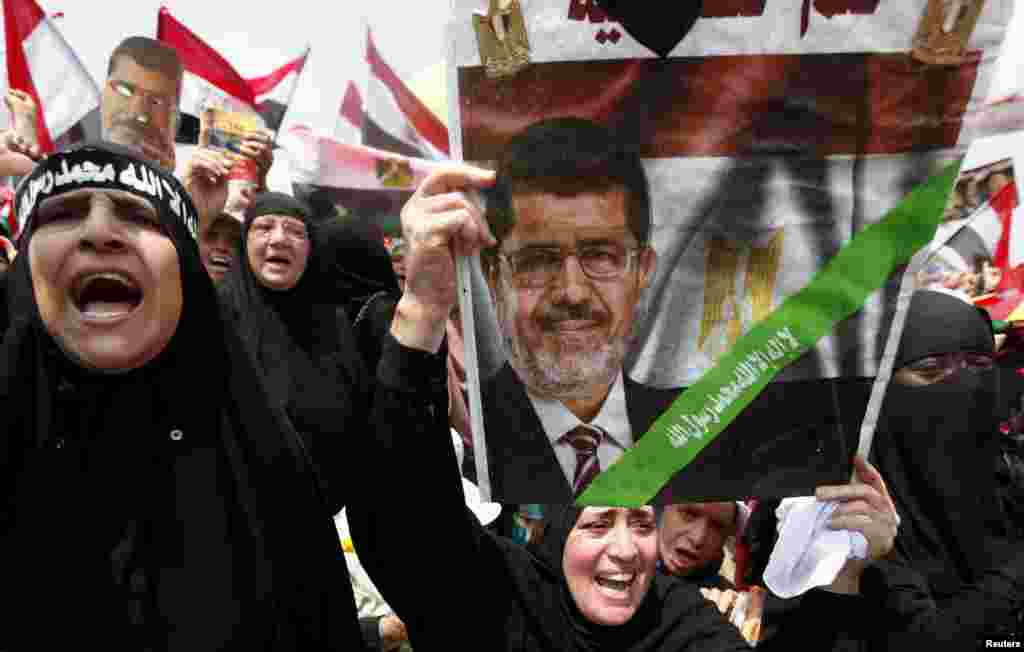 A supporter of deposed Egyptian President Mohamed Morsi holds up a sign with an image of Morsi as they protest at the Rabaa el-Adawiya square where they are camping in Cairo, July 19, 2013. 