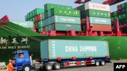 Truk pembawa peti kemas meninggalkan pelabuhan Qingdao, di provinsi Liaoning (20/1). (Foto: AFP)