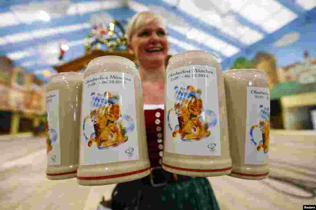 A waitress presents the official Oktoberfest beer mugs during a presentation in Munich, Germany. Oktoberfest, the world's biggest beer festival, runs from Sept. 21 until Oct. 6 this year.