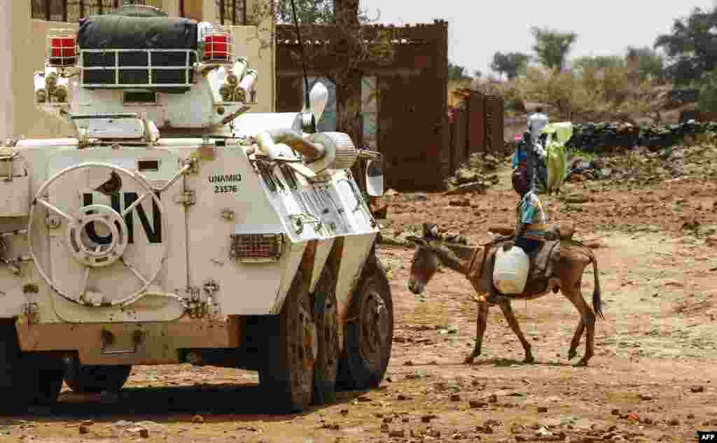 Seorang remaja Sudan menaiki keledai melewati kendaraan militer pasukan penjaga perdamaian PBB (UNAMID) di Golo, Darfur tengah.