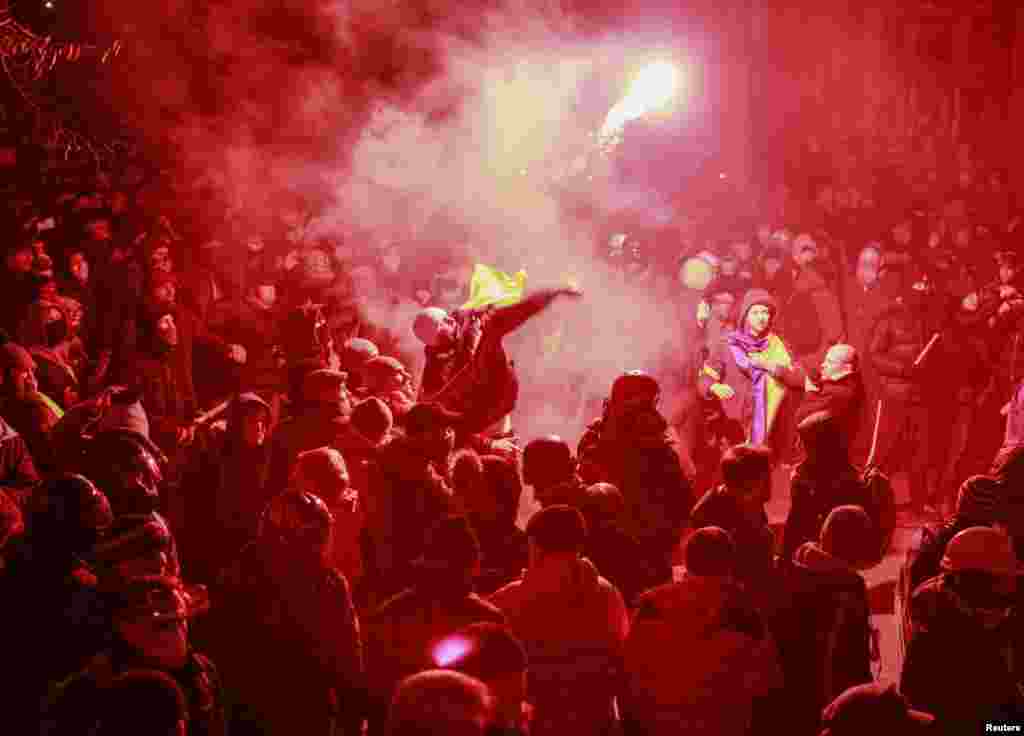A man throws a flare in the direction of Interior Ministry members during a rally held by supporters of EU integration in Kyiv, Dec. 1, 2013.