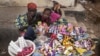 Girls selling sweets watch from their makeshift kiosk - as other boys and girls their age [not pictured] attend school - amid great poverty, in the city of Makeni in Sierra Leone, April 20, 2012.