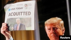 Rais wa zamani wa Marekani Donald Trump akionyesha gazeti la USA Today likiwa na habari za Baraza la Seneti kumuondolea mashtaka kwa tuhuma za kutumia vibaya madaraka na kuingilia kati Bunge la Marekani, Washington, Marekani, February 6, 2020. REUTERS/Leah Millis