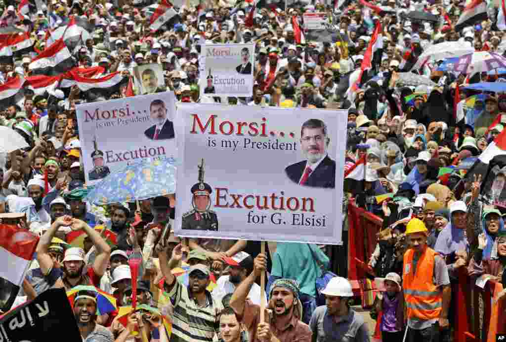 Supporters of Egypt's ousted President Mohammed Morsi hold up placards as they shout slogans during a demonstration where protesters have installed their camp, at Nasr City, Cairo, Egypt, July 19, 2013. 