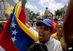 An opposition member waves a Venezuelan flag as National Assembly President Julio Borges speaks during a special public session at a square in Caracas, Venezuela, April 1, 2017.