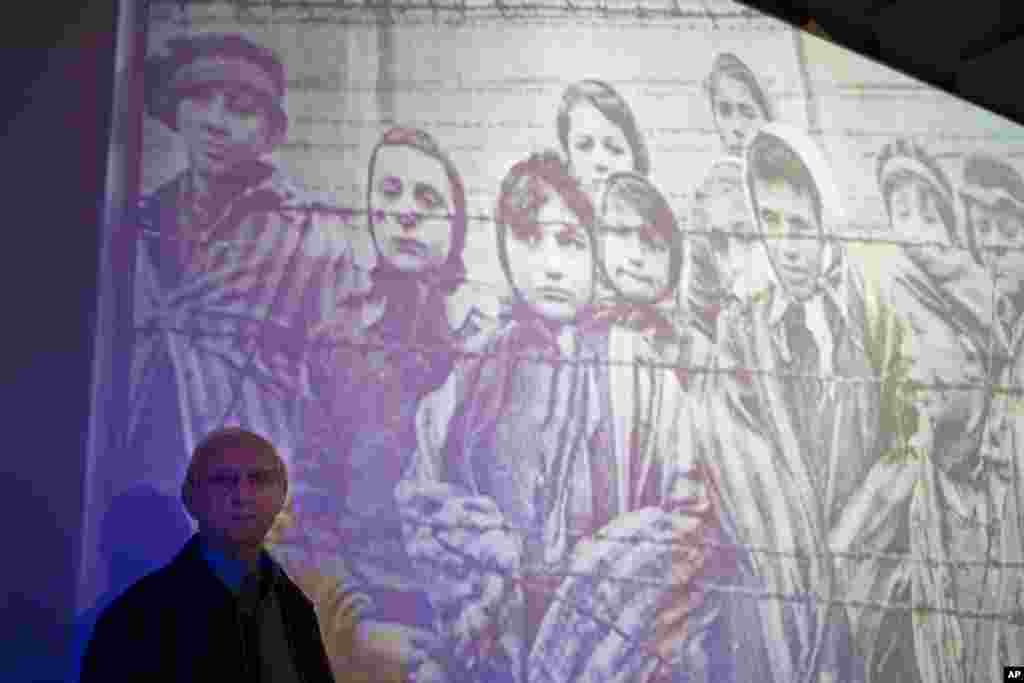 Penyintas Auschwitz-Birkenau Holocaust, Tomy Shacham, berpose sebelah foto yang menunjukkan dirinya, sebelah kiri, dalam upacara peringatan holocaust internasional di institut studi holocaust internasional Massuah (27/1) di Kibbutz Tel Yitzhak, Israel tengah. (AP/Ariel Schalit)