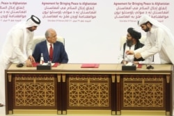 FILE - U.S. peace envoy Zalmay Khalilzad, left, and Mullah Abdul Ghani Baradar, the Taliban group's top political leader sign a peace agreement between Taliban and U.S. officials in Doha, Qatar, Feb. 29, 2020.