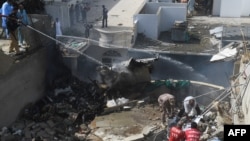 Petugas berupaya memadamkan api kebakaran dari pesawat milik maskapai Pakistan International Airlines (PIA) yang jatuh di kawasan permukiman di Karachi, Pakistan, 22 Mei 2020.