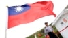 FILE - A Taiwan Coast Guard officer stands guard under a Taiwanese flag in the East China Sea, north of Taiwan, April 9, 2016.
