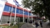 FILE - People sit outside the building which used to house a Coca-Cola bottling plant before the 1959 revolution in Havana.