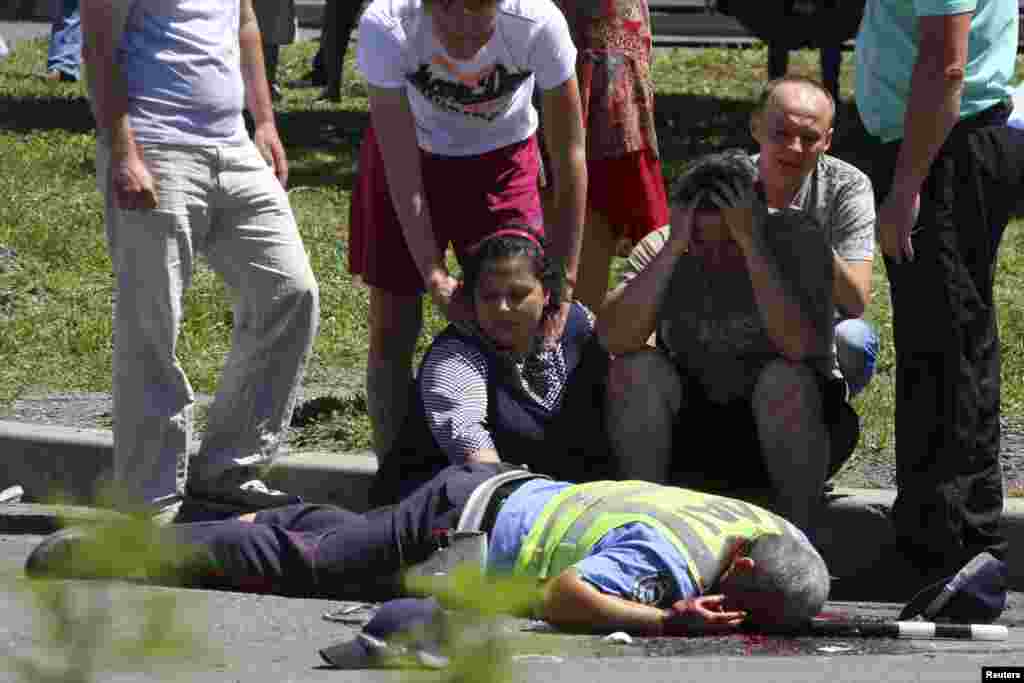 Relatives grieve after traffic police officers were attacked by unknown assailants in the eastern Ukrainian city of Donetsk, July 3, 2014.