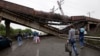 People walk under a destroyed railroad bridge over a main road leading into Donetsk, near the village of Novobakhmutivka, North of Donetsk, eastern Ukraine, July 7, 2014.