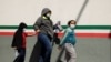 Migrantes centroamericanos en busca de asilo en EE.UU., que fueron transportados en avión desde Brownsville a El Paso, Texas, y deportados de Estados Unidos, cruzan el puente fronterizo internacional Paso del Norte, en Ciudad Juárez, México, el 19 de marz