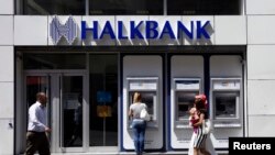 FILE - A customer uses an automated teller machine at a branch of Halkbank in Istanbul, Aug. 15, 2014. 