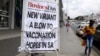 FILE PHOTO: A woman walks past newspaper billboards during the coronavirus disease (COVID-19) outbreak in Johannesburg, South Africa, Feb. 8, 2021.