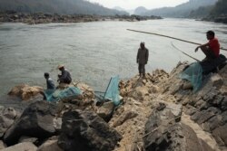 FILE - Fishermen lay their nets on the Mekong River near Luang Prabang close to the site of an approved Laos dam site, Feb. 8, 2020.