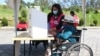Una mujer indígena en silla de ruedas es asistida en un colegio electoral en Cuenca, Ecuador, el 11 de abril de 2021.