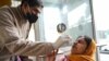 A health worker collects a nasal swab sample from a woman to test for COVID-19 at a hospital in Amritsar on Jan. 5, 2023.