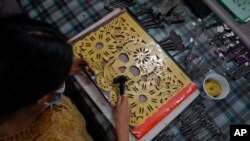 মেক্সিকো সিটির জোকিমিলকো বোরো’র এক কারখানায় “পাপেল পিকাডো” তৈরিতে এক নারী প্লাস্টিকের নকশা ব্যবহার করছেন, যেগুলো ডে অফ দ্য ডেড-এ বেদীতে ব্যবহারের জন্য টিস্যু পেপার কেটে সাজসজ্জা তৈরির প্রথাগত প্রক্রিয়া, ২৭ অক্টোবর ২০২২।