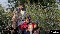 Des migrants syriens et la clôture barbelée à la frontière entre la Hongrie et la Serbie, près deRöszke, le 27 août 2015. (REUTERS/Bernardett Szabo - RTX1XX6V)