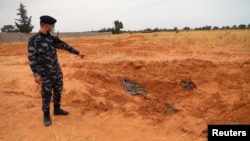 Seorang anggota pasukan keamanan Libya menunjukkan lokasi makam masal di Kota Tarhouna, Libya, 11 Juni 2020. Mohamed al-Kani, pemimpin milisi yang dituduh bertanggung jawab atas pembunuhan massal, tewas dalam baku tembak, Selasa, 27 Juli 2021.